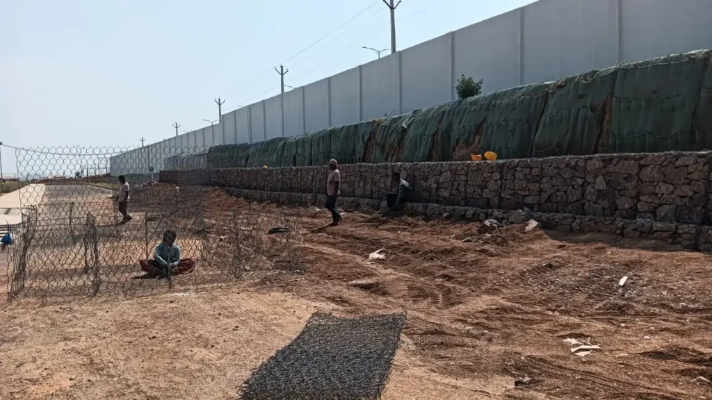 Workers building a gabion wall with stone-filled cages