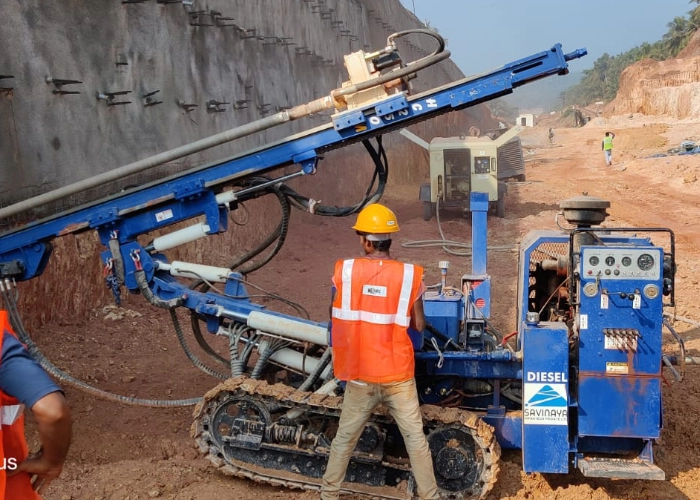Worker operating rig for soil nailing drill on slope