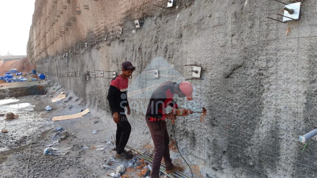 Workers installing soil nailing anchors on reinforced retaining wall
